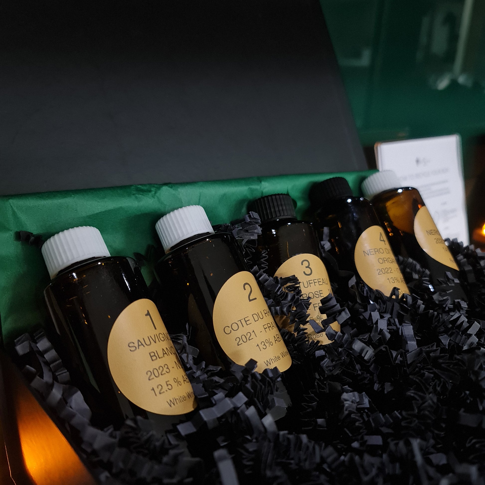 Vinesine At-home wine tasting kit in the premium black gift box with 5 miniature bottles of wine slighly  lifeted up to show case the labels.